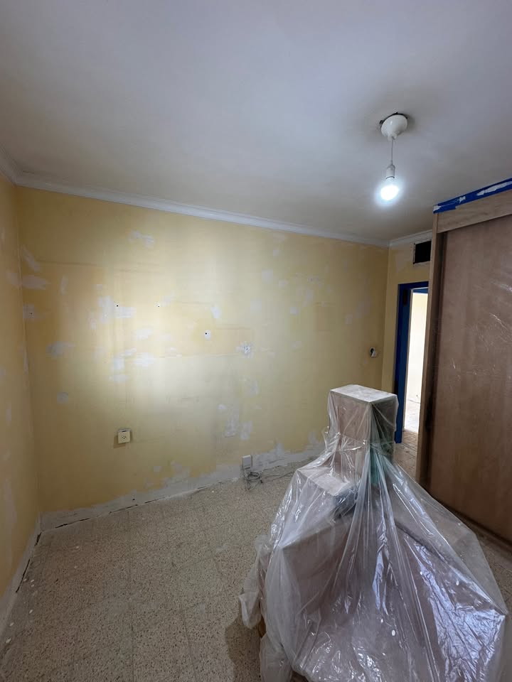 חדר עם רצפה מכוסה ביריעות הגנה וקירות בהכנה לצבע